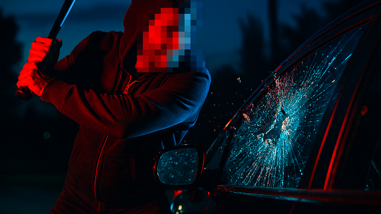 Mężczyzna z pałką wybija szybę w samochodzie