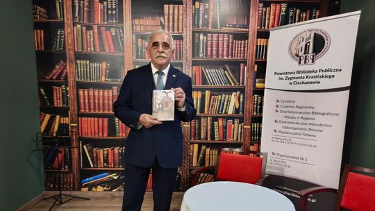 Lech Zduńczyk trzyma książkę o Mieczysławie Kurzypińskim w Powiatowej Bibliotece Publicznej w Ciechanowie