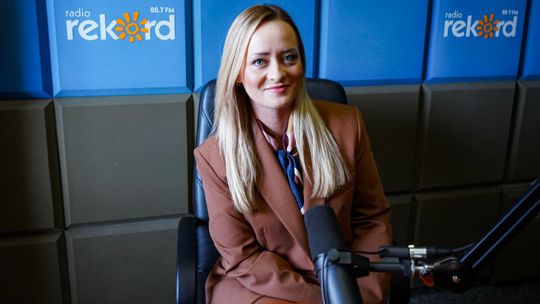 Emilia Olszewska w brązowej marynarce przy mikrofonie w studiu Radia Rekord Mazowsze.