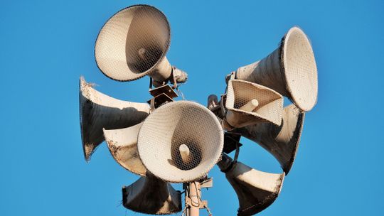 Zespół głośników tubowych systemu alarmowego na tle niebieskiego nieba.