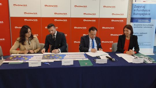 Cztery osoby przy stole z dokumentami podczas spotkania dotyczącego funduszy europejskich