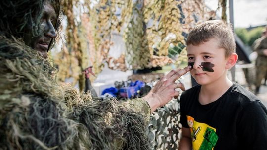 Żołnierz maluje twarz dziecka podczas pikniku militarnego