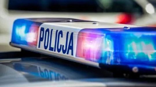 Niebieskie i czerwone światła sygnalizacyjne na dachu radiowozu z napisem Policja.