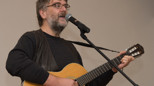 Wojtek Gęsicki z gitarą przed mikrofonem