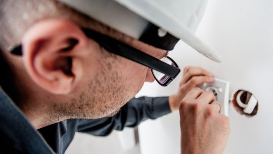 Elektryk wymienia gniazdko w ścianie