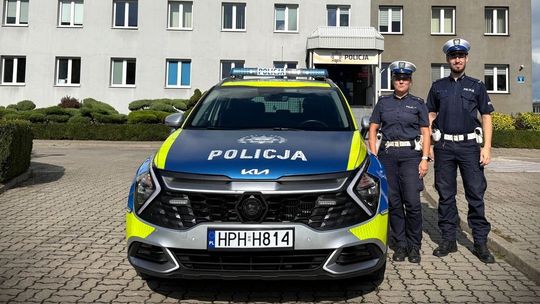 Mł. asp. Małgorzata Piotrowska i sierż. Patryk Trzciński stoją obok radiowozu przed Komendą Powiatową Policji w Przasnyszu