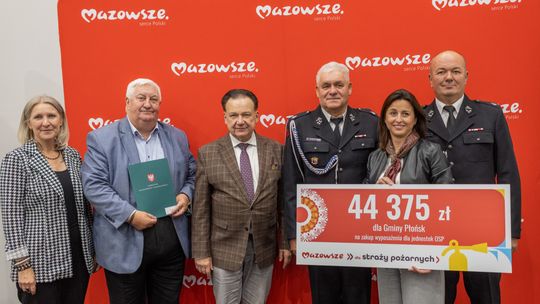 Sześć osób, w tym dwóch strażaków w mundurach, pozuje z tablicą na kwotę 44 375 zł dla gminy Płońsk na zakup wyposażenia dla OSP.