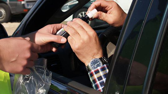Funkcjonariusz podaje kierowcy alkomat