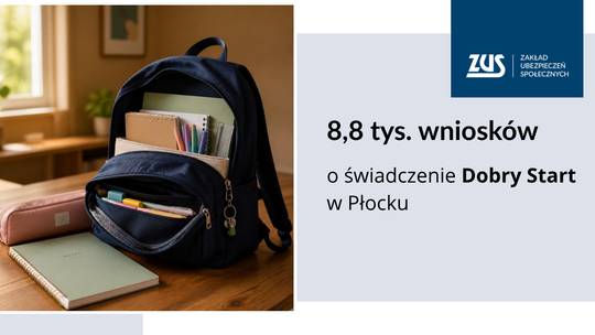 Granatowy plecak szkolny wypełniony zeszytami i przyborami stojący na drewnianym biurku.