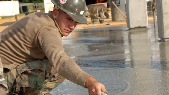 Pracownik wygładza beton na posadzce