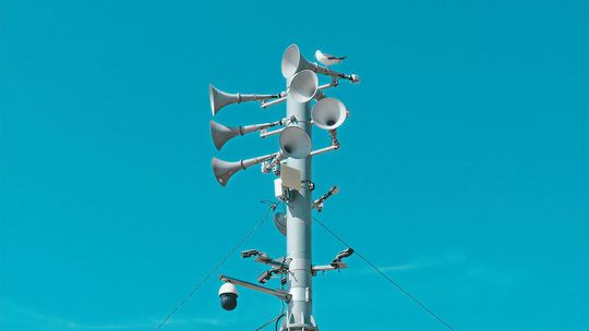 Syrena alarmowa na maszcie na tle nieba - test syren alarmowych w Ciechanowie
