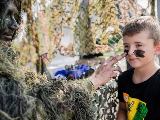Żołnierz maluje twarz dziecka podczas pikniku militarnego