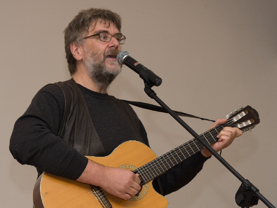 Wojtek Gęsicki z gitarą przed mikrofonem