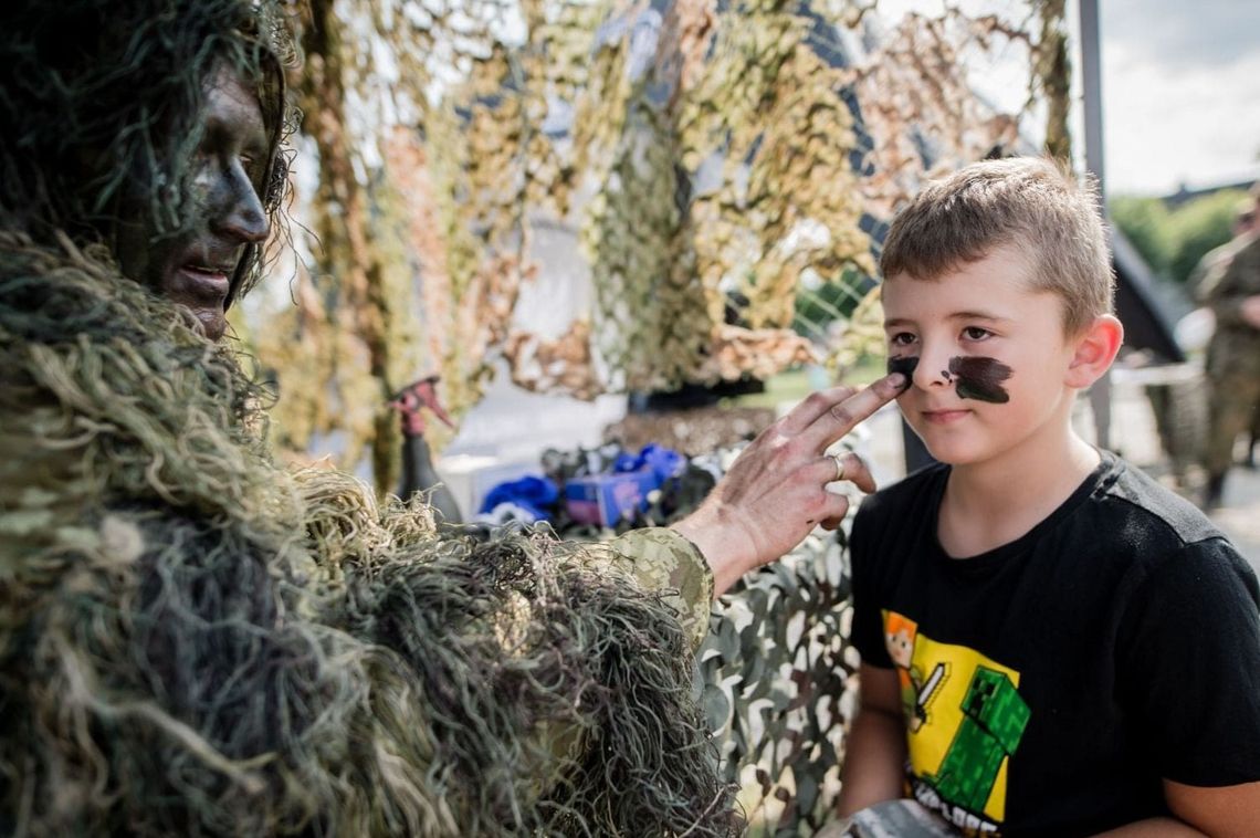 Żołnierz maluje twarz dziecka podczas pikniku militarnego
