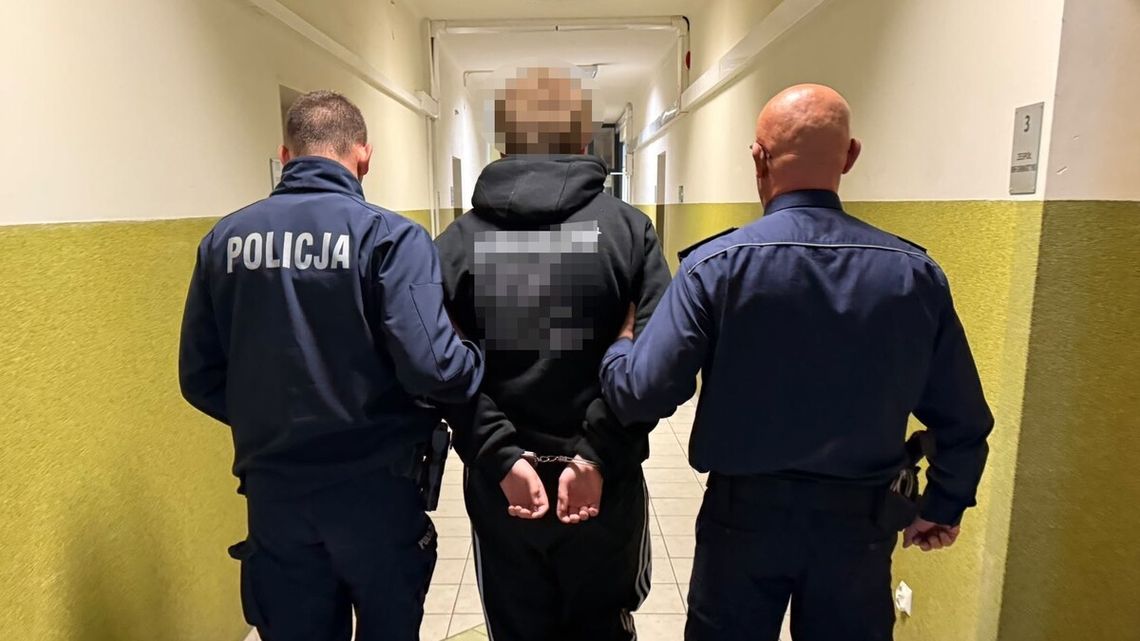 Dwóch policjantów prowadzi korytarzem osobę z rękami skutymi za plecami.