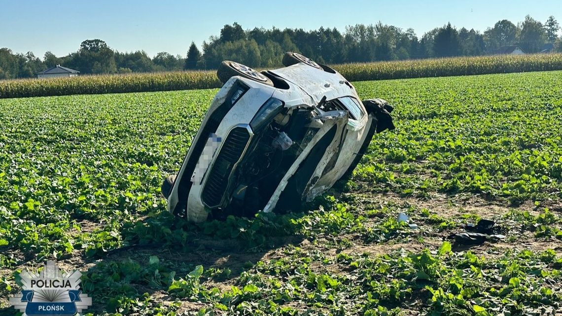 Uszkodzona biała skoda przewrócona na polu, z zamazaną tablicą rejestracyjną