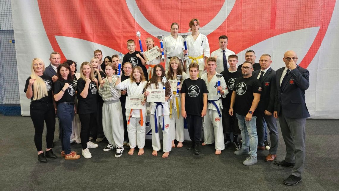 Zawodnicy w białych kimonach z medalami na szyjach podczas mistrzostw w karate kyokushin w Ciechanowie.