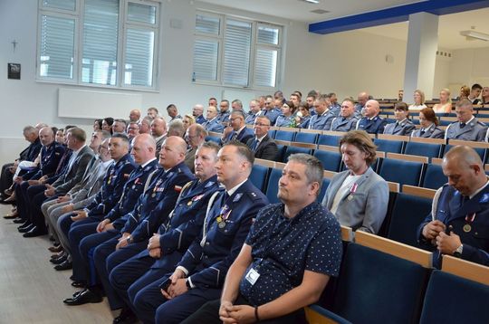 106 lat Policji Państwowej i 100 lat kobiet w służbie. Uroczystości w Mławie Uroczystości Święta Policji w Mławie, w tle wyróżnieni policjanci i goście, obchody 100-lecia kobiet w Policji.