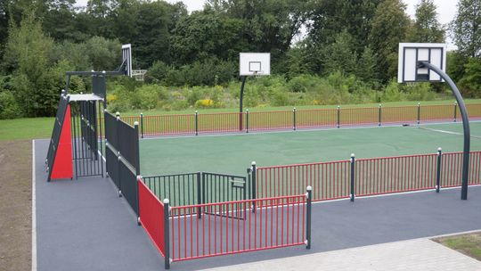 Teren rekreacyjny przy Zespole Szkół nr 4 w Mławie z siłownią zewnętrzną i stołami do gier.