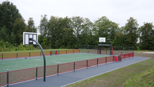 Teren rekreacyjny przy Zespole Szkół nr 4 w Mławie z siłownią zewnętrzną i stołami do gier.