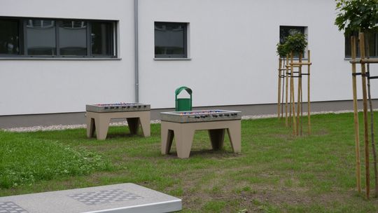 Teren rekreacyjny przy Zespole Szkół nr 4 w Mławie z siłownią zewnętrzną i stołami do gier.